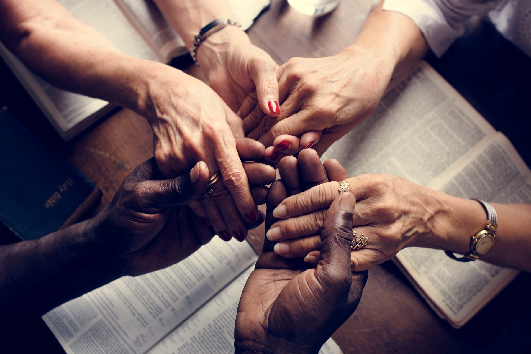 Mãos de várias pessoas unidas sobre uma mesa